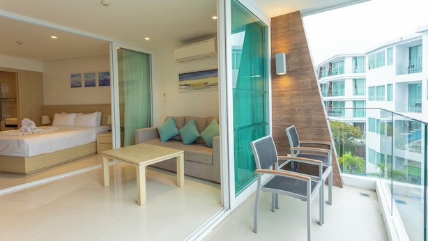 A modern hotel room with a bed, sofa, and a balcony with glass railings. - Sea View Beach Dinning Beach Front c115 (Rawai)