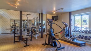 A gym with cardio machines, weightlifting equipment, and a mirror wall.