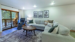 A living room with a sofa, armchair, and coffee table. There are three framed pictures on the wall.