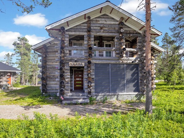 A log cabin with a front door labeled 'NAAVA' and a number '2' on the door.