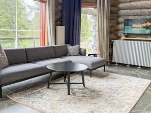 A modern living room with a sectional sofa, a round coffee table, and a television on a stone wall.