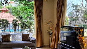 A living room with a sofa, TV, and a glass coffee table. - Khushana Villa by Baywatch stayzz (Chennai)