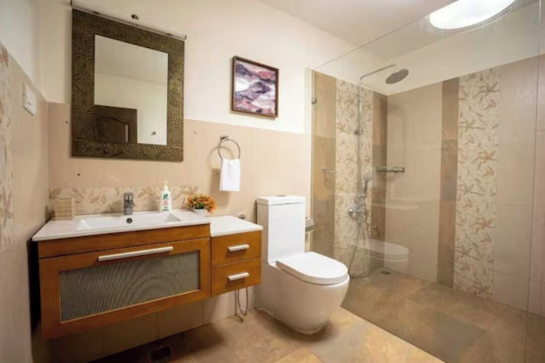 Un baño con tocador de madera, inodoro, ducha y espejo.