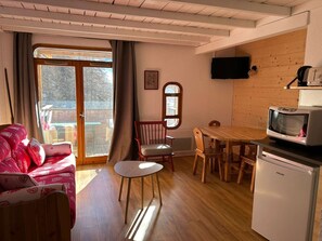 Un salon confortable avec un canapé, une table à manger et des chaises, un téléviseur et un réfrigérateur.