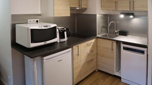 Eine kleine Küche mit Mikrowelle, Kaffeemaschine und Geschirrspüler.