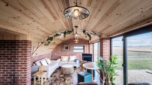 Un salon chaleureux avec une cheminée en briques, un canapé, une table basse et un téléviseur.