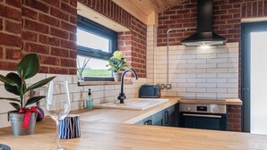 Une cuisine avec un mur en briques, une fenêtre, un évier, une cuisinière et un plan de travail.