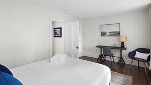 A hotel room with a bed, a desk, a chair, and a picture on the wall. - Enjoy Boston, Private Patio On Montgomery Park (Boston)