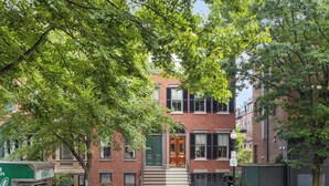 A two-story brick building with a green door and steps leading to the entrance. - Enjoy Boston, Private Patio On Montgomery Park (Boston)