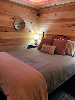 Relax in a serene bedroom with a plush bed, round mirror, and cozy reading nook.
