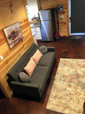 Cozy living space with a sofa, rug, and functional kitchenette.