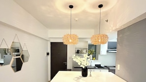Una cocina moderna con una isla central, luces colgantes y un espejo geométrico en la pared.