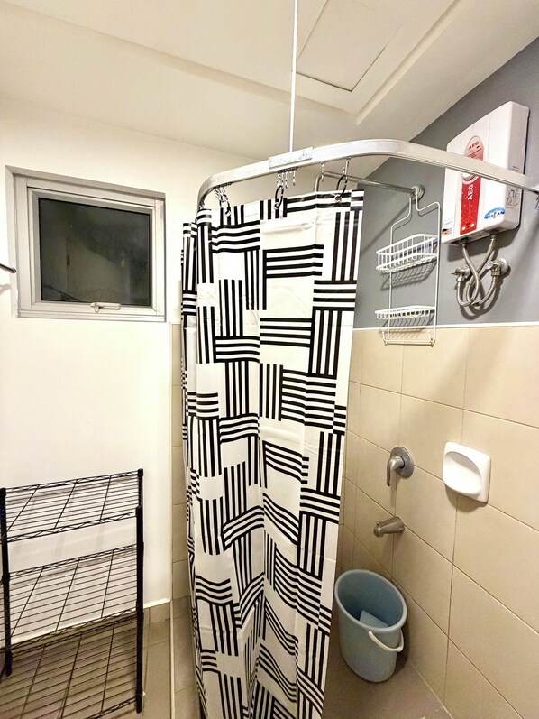 A bathroom with a shower curtain, a window, a towel rack, a hand dryer, and a waste bin. - Avida Towers Davao Near Roxas Market (Davao)