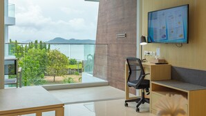 A modern office space with a large window overlooking a scenic view, a desk, a chair, and a mounted digital menu board. - Sea View Beach Dinning Beach Front c113 (Rawai)