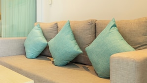 A beige sofa with three teal cushions. - Sea View Beach Dinning Beach Front c113 (Rawai)