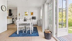 A bright, open-plan living space with a dining area, kitchen, and large windows.
