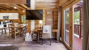 Ein Ferienhaus-Innenraum mit Essbereich, Küche und einem an der Wand befestigten Fernseher.
