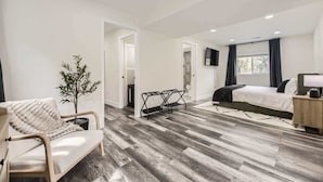A modern hotel room with a bed, a seating area with a chair and a small table, a potted plant, and a television on the wall. - Aspen A-Frame Hot Tub Mountain Retreat Evergreen (Evergreen)