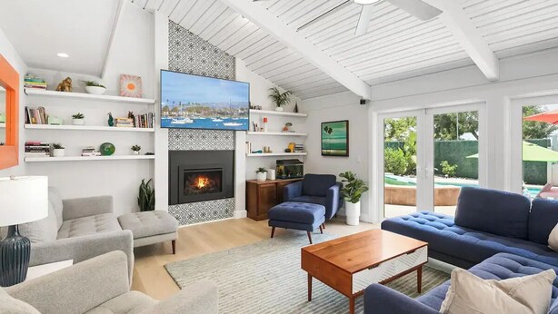 A modern living room with a fireplace, comfortable seating, and a view of the outdoors.