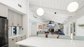 A modern kitchen with a large island, white cabinetry, and a built-in oven.
