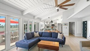 A spacious living room with a sectional sofa, a wooden coffee table, and a ceiling fan.