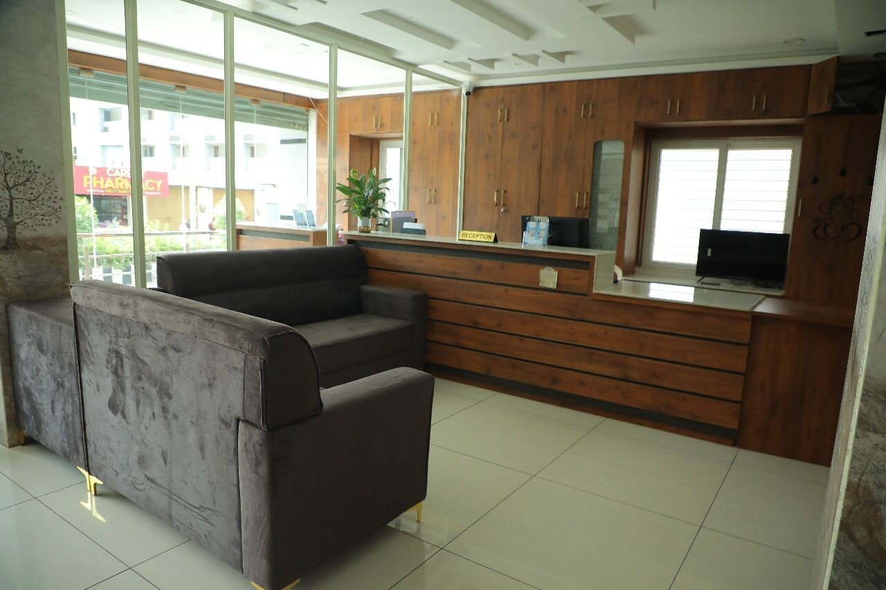 A reception area with a grey sofa, wooden cabinets, a reception desk, and a large window providing a view of the outside.