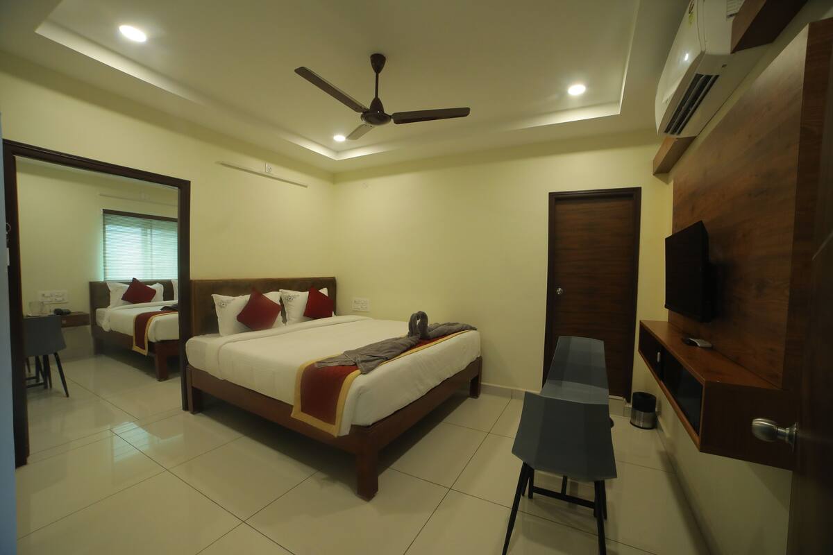 A hotel room with a bed, a desk, a chair, a TV, and a ceiling fan.
