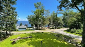 A residential property with a grassy yard, a wooden deck, and a view of the water.