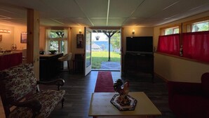 Un amplio salón con un sofá, una mesa de centro, un televisor y vistas a través de puertas de cristal.