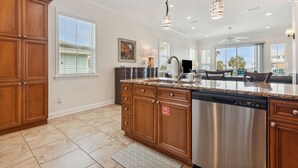 A spacious kitchen with wooden cabinets, a stainless steel dishwasher, and pendant lighting. - Amelia Sunrise - Oceanview, Bikes, & Beach Access (Fernandina Beach)