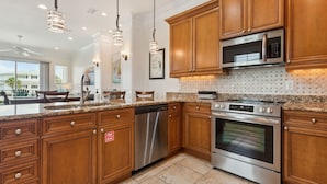 A modern kitchen with wooden cabinets, stainless steel appliances, and pendant lighting. - Amelia Sunrise - Oceanview, Bikes, & Beach Access (Fernandina Beach)