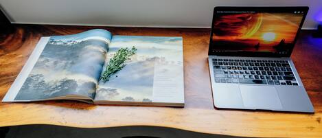 A laptop on a wooden desk with a book beside it.