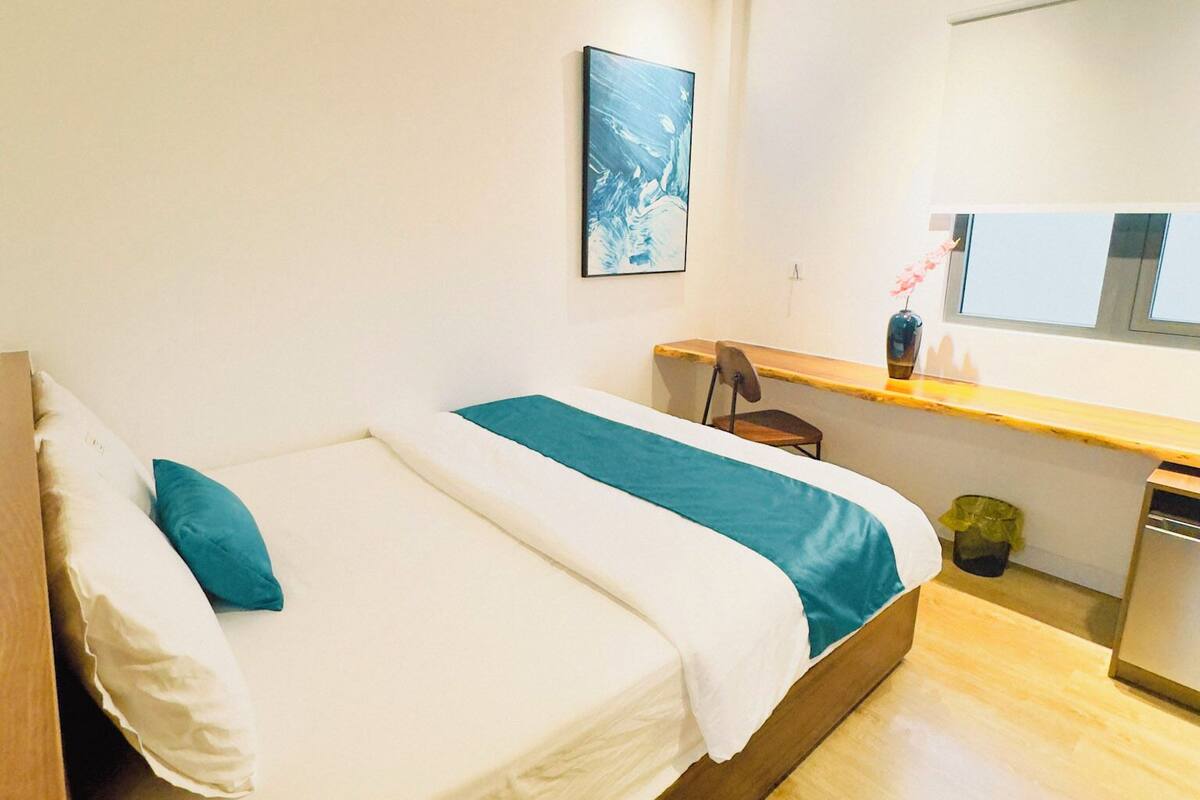 Une petite pièce propre, avec un lit, un bureau et une fenêtre.