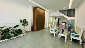 A spacious living area with a staircase, seating, and potted plants. - Urban Hotel (Ho Chi Minh City)