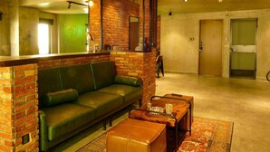 A modern lounge area with a green leather sofa, a wooden coffee table, and a patterned rug. - Urban Hotel (Ho Chi Minh City)