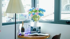 A table with a bottle of champagne, two glasses, a vase with flowers, and a book titled "Angers". - Urban Hotel (Ho Chi Minh City)