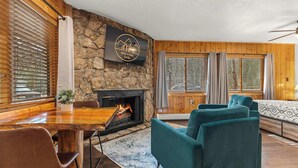 Una sala de estar acogedora con chimenea de piedra, paredes de madera y un espacio de estar confortable.