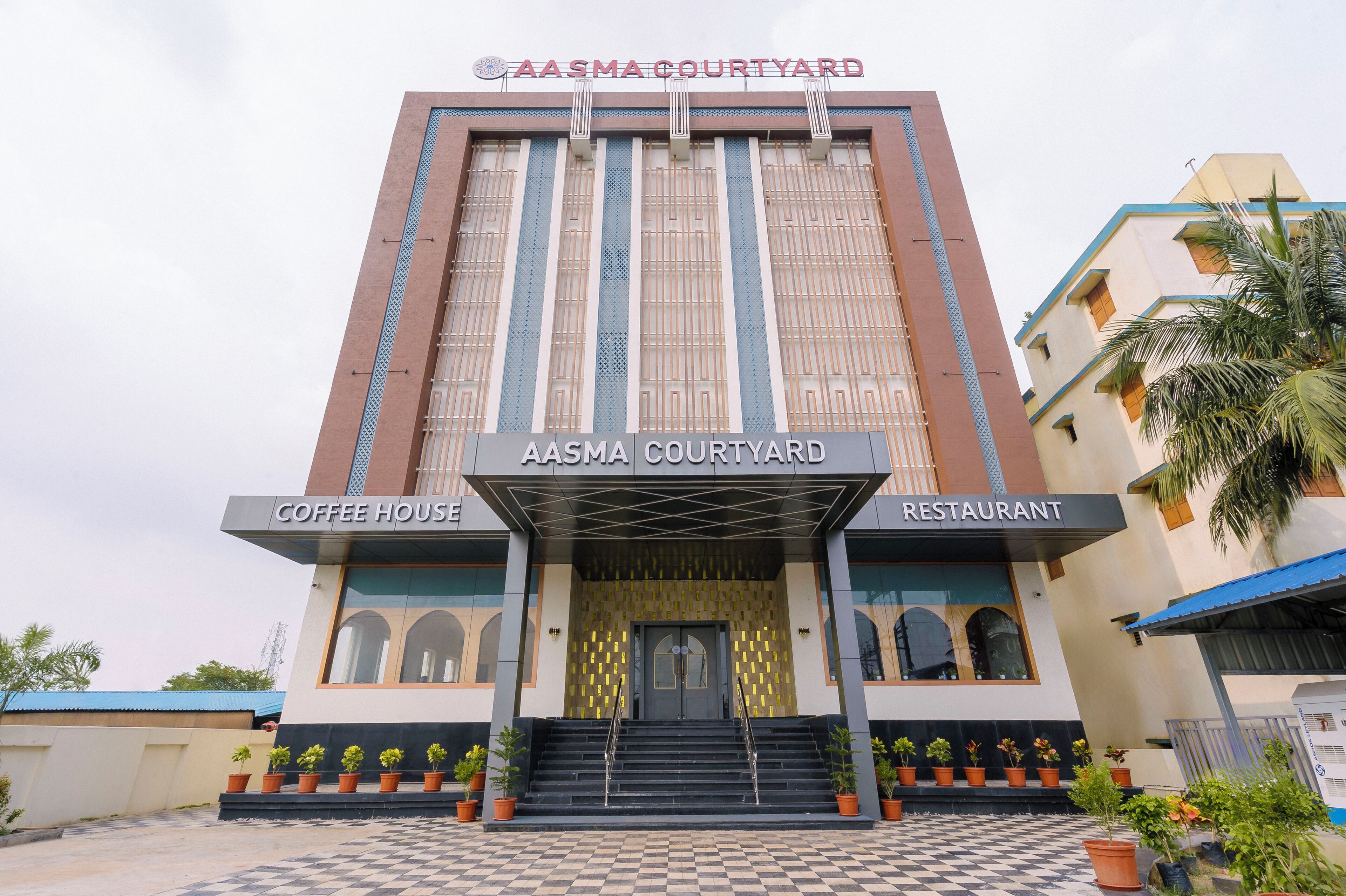 A building with a sign reading 'AASMA COURTYARD' and 'COFFEE HOUSE' and 'RESTAURANT' indicating the presence of these facilities.