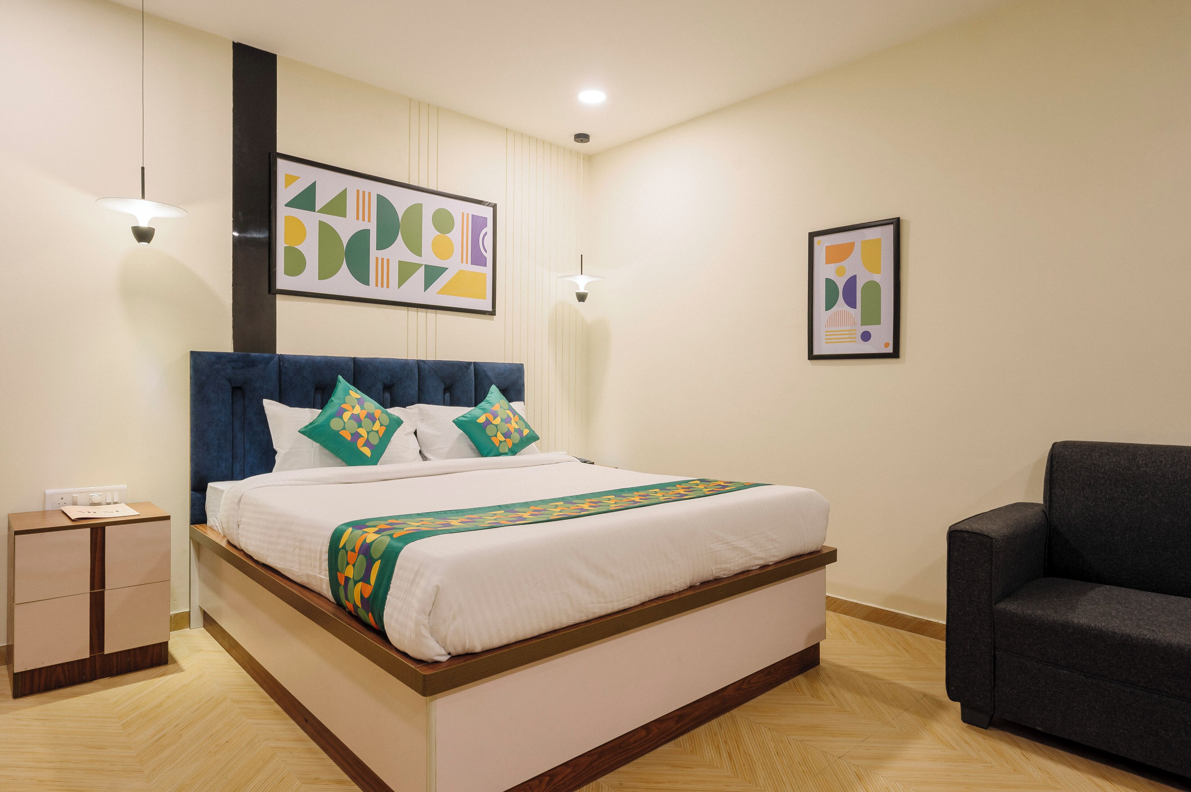 A neatly arranged hotel room with a bed, bedside table, and a dark-colored sofa.