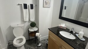 A bathroom with a toilet, sink, mirror, towel rack, and a small potted plant.