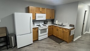 A kitchen with wooden cabinets, a white refrigerator, a microwave, an oven, and a sink.