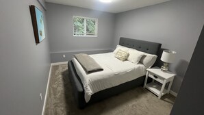 A bedroom with a bed, bedside table, and a window.