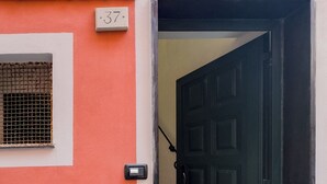 Una porta con maniglia in metallo, una piccola finestra con grate e un cartello con il numero 37 appeso al muro.