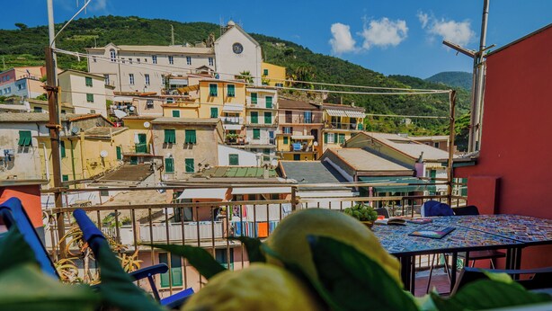 Una terrazza con tavolo e sedie, con vista su una collina e degli edifici.