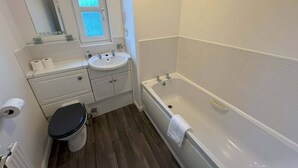 Un baño con inodoro, lavabo, espejo y bañera.