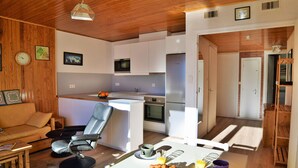 A modern kitchen with white cabinets, a Bosch refrigerator, and a microwave. There is a dining area with a table set for breakfast, including croissants and orange juice.
