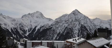 A mountain village with snow-covered buildings and a prominent peak in the background.