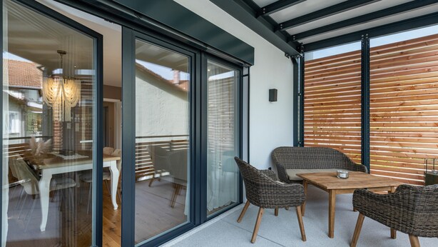 A modern outdoor patio with glass doors, wicker furniture, and a wooden slatted wall. - Holiday flat ‘Bei Thérèse’ with balcony and Wi-Fi (Miltach)