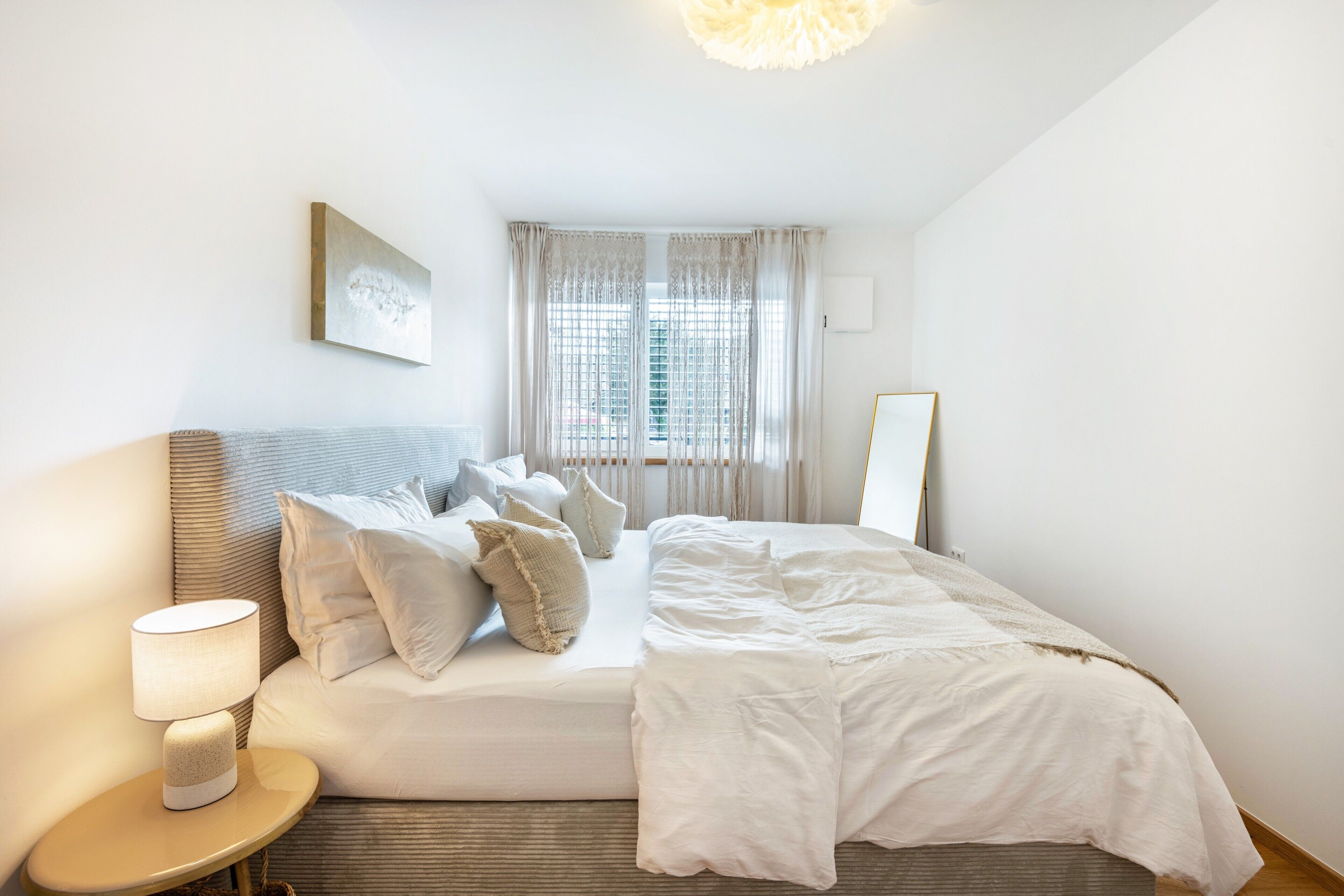 A hotel room with a bed, a bedside lamp, a window with curtains, and a wall-mounted picture.