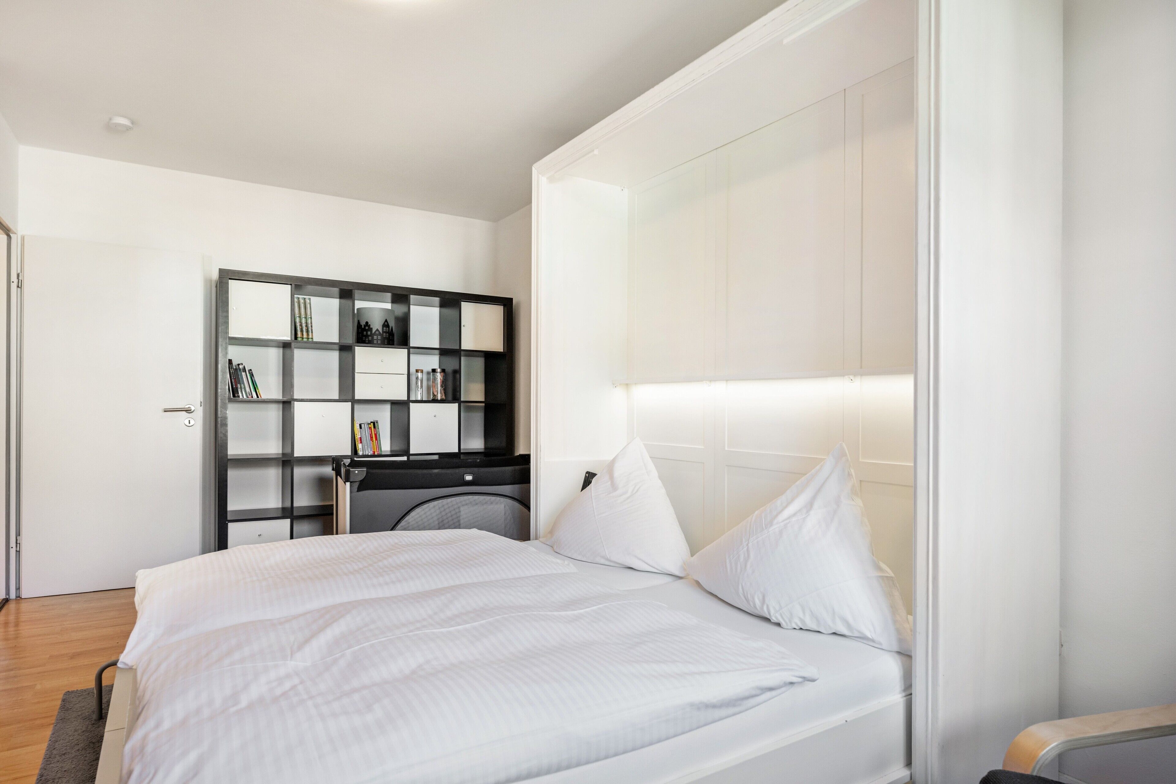 Ein modernes Schlafzimmer mit einem großen Bett, einem Einbauschrank und einem Nachttisch.